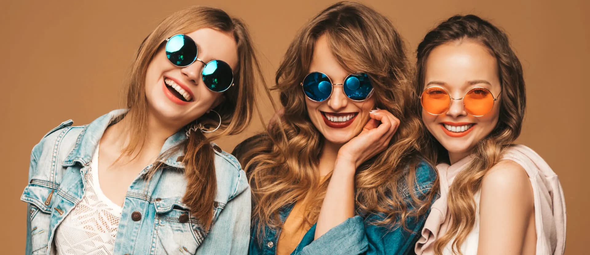 Three friends wearing denim jackets and sunglasses outdoors